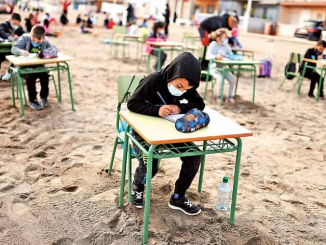 Niños toman clases a la orilla del mar en España.